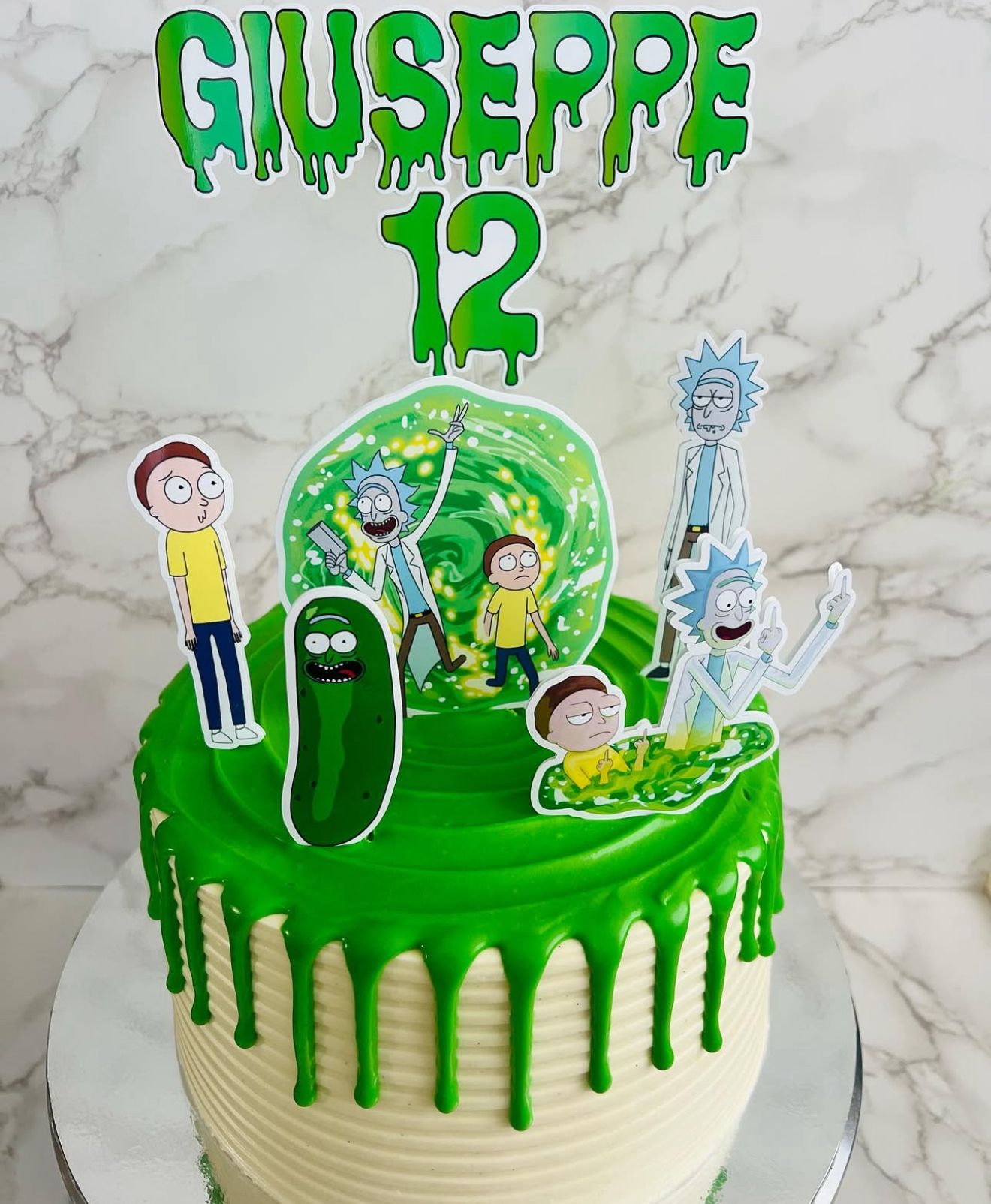 Birthday cake with green icing and 'Giuseppe 12' text on a marble surface