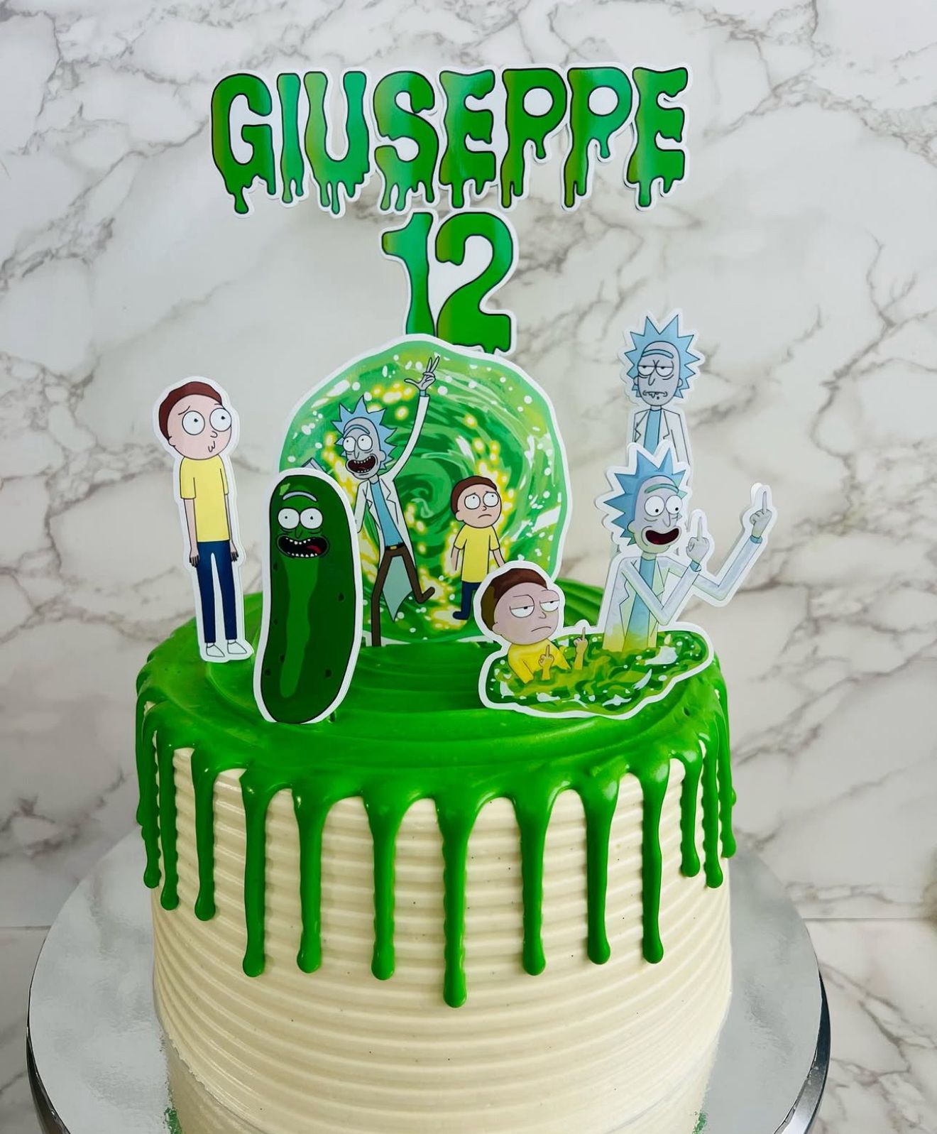 Birthday cake with green icing and cartoon character toppers on a marble background